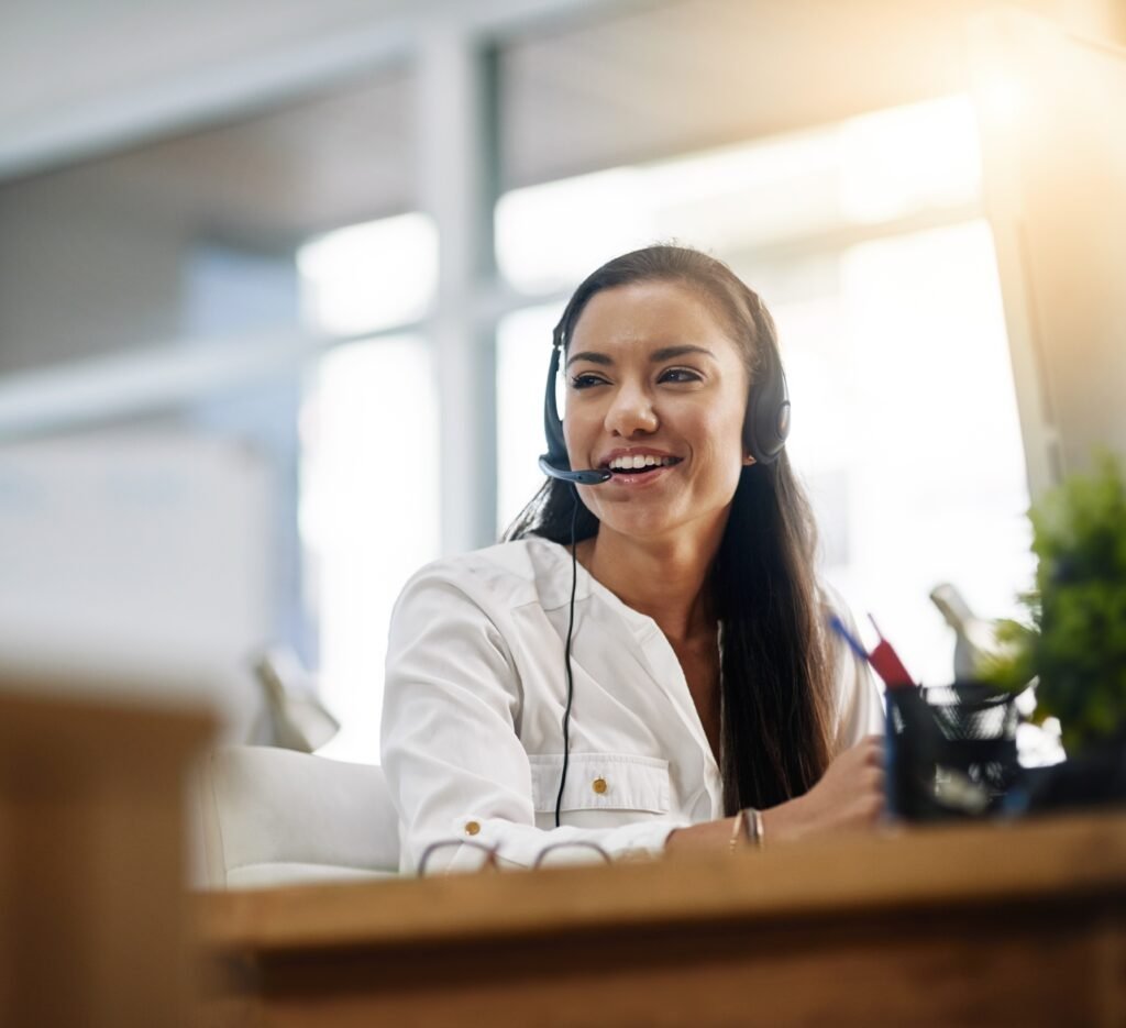 customer service rep at a desk smiling with headset on