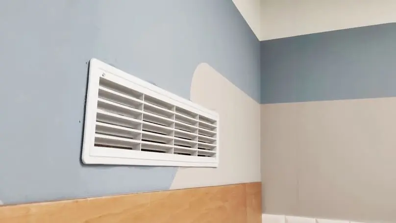 A clean room features a white air vent on a wall, ideal for learning how to clean vents in house.