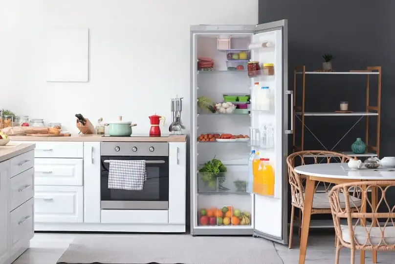 A lit kitchen with an open, well-stocked refrigerator, ready for learning how to deep clean a fridge